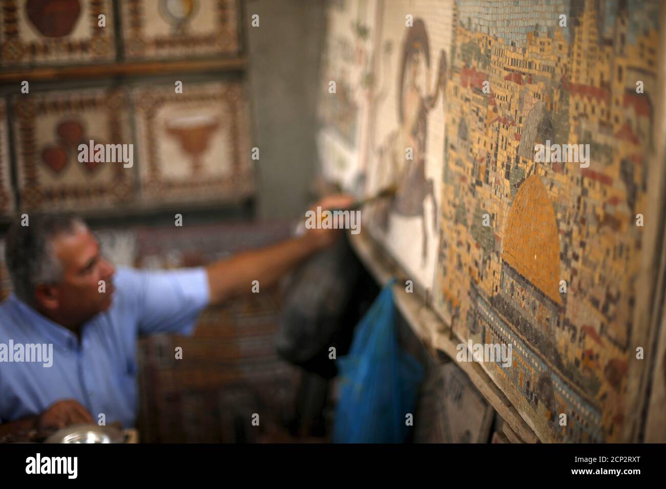 Archeology Nafez Abed cleans sculptures at his workroom, at Shati refugee camp in Gaza City, November 8, 2015. Nafez Abed's cramped workroom is filled with sculptures and intricate mosaics decorated with patterns from the Byzantine, Greek and Roman periods. It is an emporium of Middle Eastern antiquity tucked away in Gaza. And none of it is real. Picture taken November 8, 2015. To match story PALESTINIANS-ARCHAEOLOGY REUTERS/Suhaib Salem Stock Photo