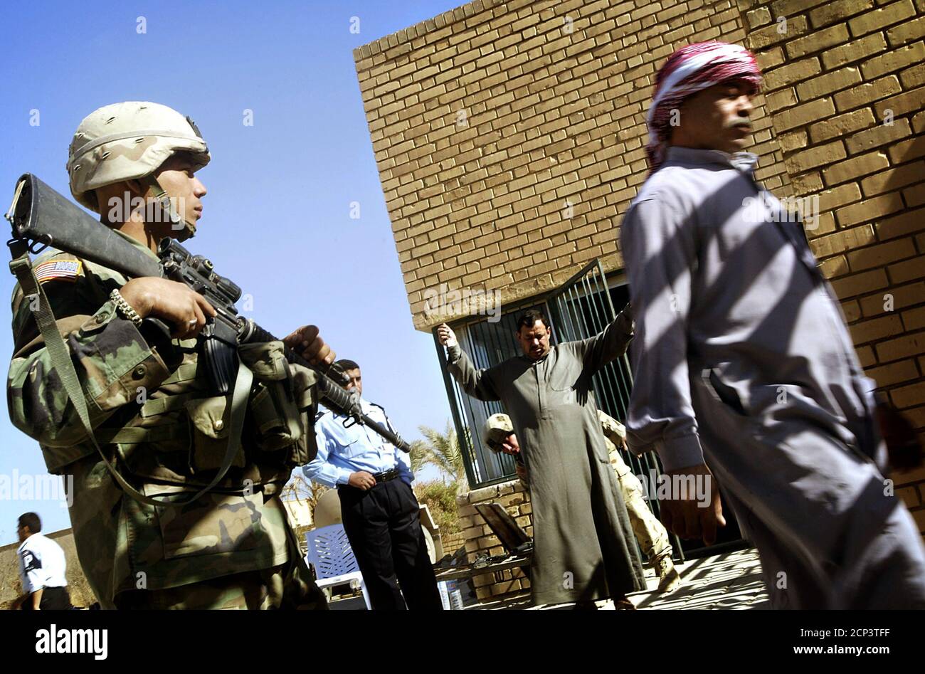 Iraqi men are searched by U.S. troops at the entrance of a police station as they wait for new identity cards to be issued in al Awja, a village outside Tikrit, 110 miles north of Baghdad, November 1, 2003. U.S. Army's 4th Infantry Division (Task Force Ironhorse) continued for the second day stepping up security in the village of al Awja where former Iraqi president Saddam Hussein was born, setting up check points, patroling with members of Iraqi Civil Defense Corps (ICDC), limiting movement with razor wire and issuing identity cards to adults that will allow them to move in and out of the vil Stock Photo