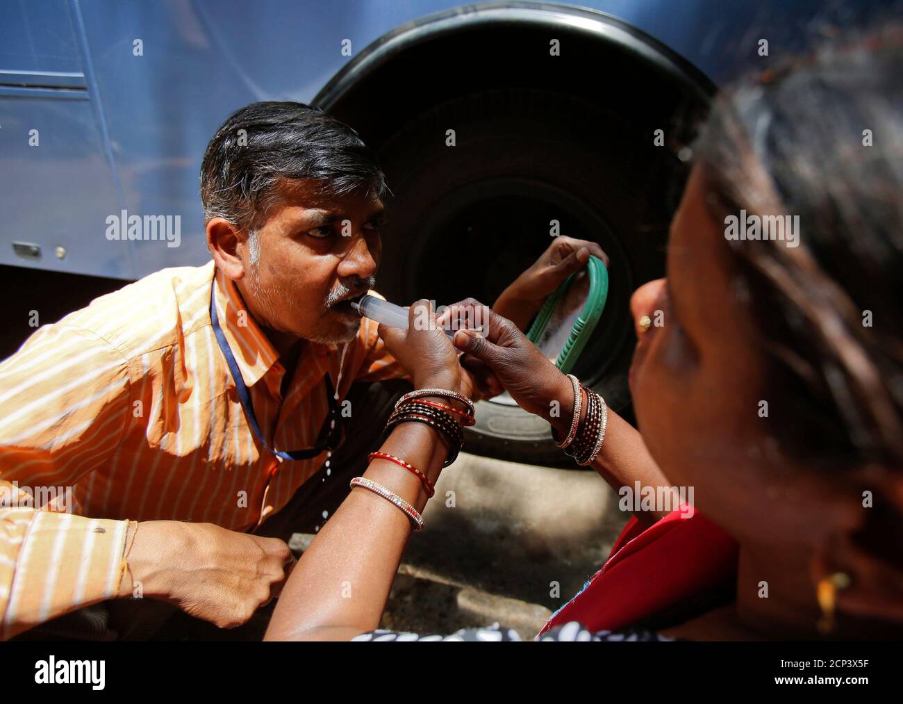 Cancer patient Ramesh Chandra Rathod, 40, is helped by his wife as he rinses his mouth with a syringe after being treated at the Tata Memorial Hospital in Mumbai April 2, 2013. India's top court dismissed Swiss drugmaker Novartis AG's attempt to win patent protection for its cancer drug Glivec, a blow to Western pharmaceutical firms targeting India to drive sales and a victory for local makers of cheap generics. REUTERS/Vivek Prakash (INDIA - Tags: BUSINESS DRUGS SOCIETY HEALTH) Stock Photo