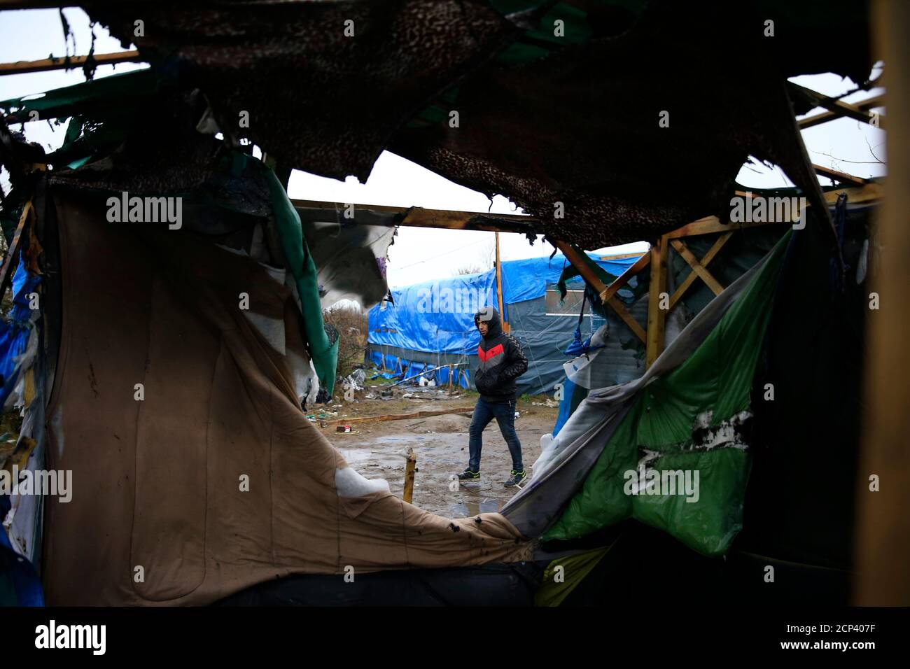 A migrant walks past makeshift shelters during the partial dismantlement of the camp for migrants called the 'Jungle' in Calais, France, March 1, 2016.   REUTERS/Pascal Rossignol Stock Photo