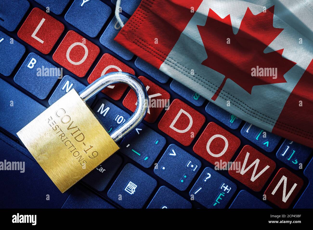 Canada COVID-19 coronavirus lockdown restrictions concept illustrated by padlock on laptop red alert keyboard buttons and face mask with Canadian flag Stock Photo