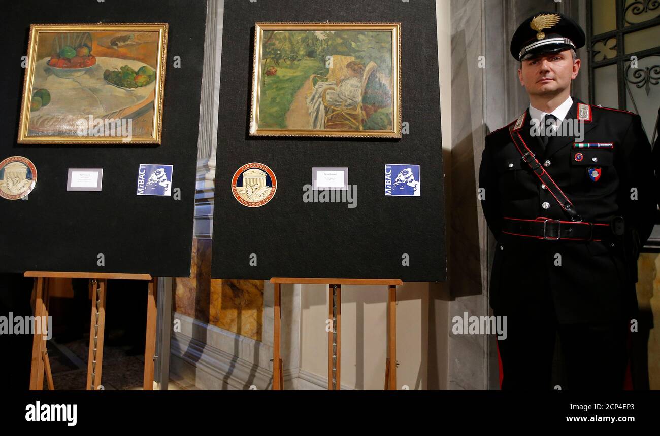 A Carabinieri police officer stands in front of two recovered paintings by  Paul Gauguin and Pierre Bonnard during a news conference in Rome, April 2,  2014. A painting by French post-Impressionist artist