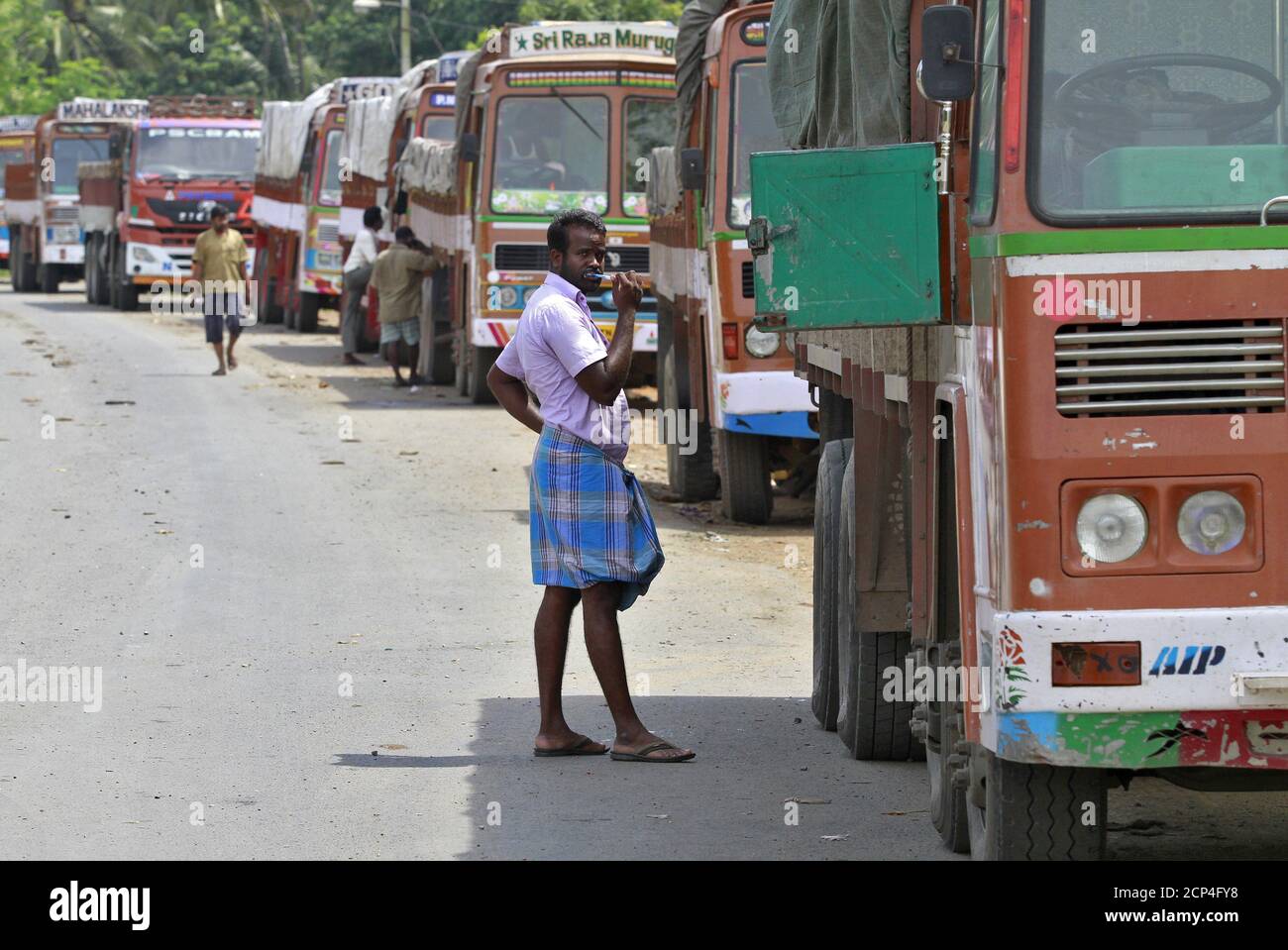 A truck driver brushes his teeth next to his parked truck while waiting to get his loads cleared to cross a checkpoint at the Commercial Taxes Department check post at Walayar in Palakkad district in southern Indian state of Kerala, India, September 5, 2015.  At the Walayar checkpoint in southern India, lines of idle trucks stretch as far as the eye can see in both directions along the tree-lined interstate highway, waiting for clearance from tax inspectors that can take days to complete. The rollout of a nationwide goods and services tax (GST) from April was supposed to sweep away hundreds of Stock Photo