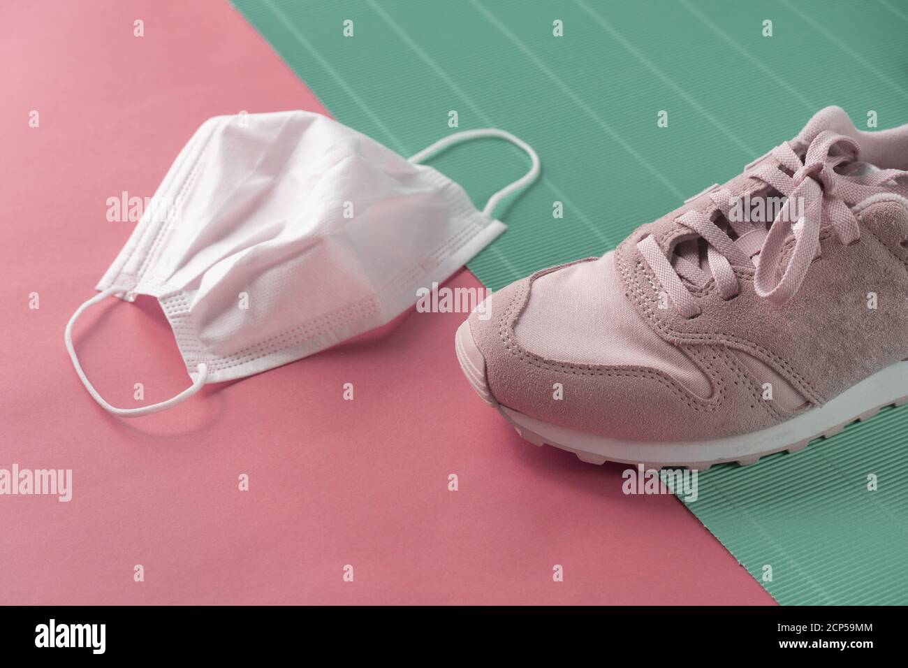 lady sport sneakeror trainer shoe with white health mask for covid 19 protection on pastel pink blue background Stock Photo