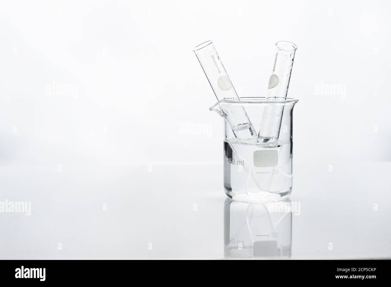 test tube in glass beaker with water in white chemistry science