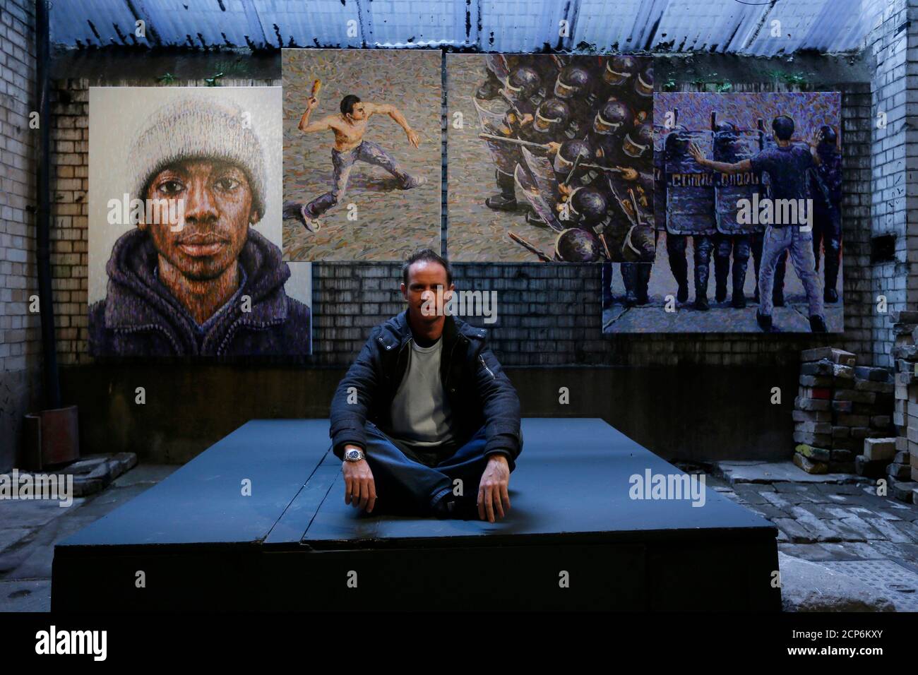 Street artist James Cochran, also known as Jimmy C, poses next to his spray painted pictures at the Pure Evil Gallery in London October 10, 2013. The paintings were originally inspired by the London riots in 2011. REUTERS/Stefan Wermuth (BRITAIN - Tags: ENTERTAINMENT SOCIETY) Stock Photo
