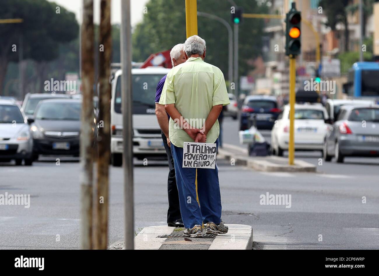 An Italian man walks as he holds a banner reading 'I'm a poor Italian, help me, thanks' in Rome, Italy, May 28, 2018. REUTERS/Alessandro Bianchi Stock Photo