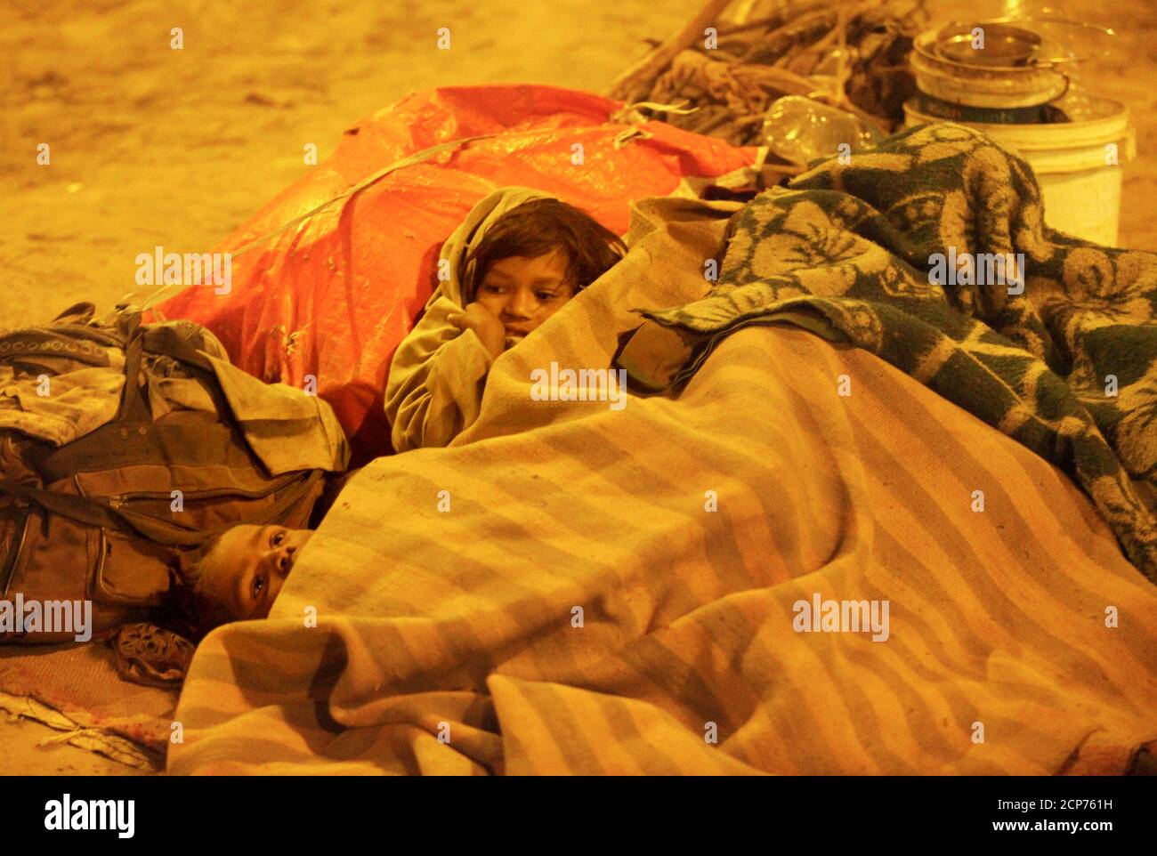 Homeless children use blankets to protect themselves from the cold under a flyover in New Delhi January 21, 2010. The Supreme Court chided the Delhi government to provide night shelters with blankets, water and mobile toilets to all homeless in the capital, local media reported. REUTERS/Reinhard Krause (INDIA - Tags: SOCIETY ENVIRONMENT) Stock Photo