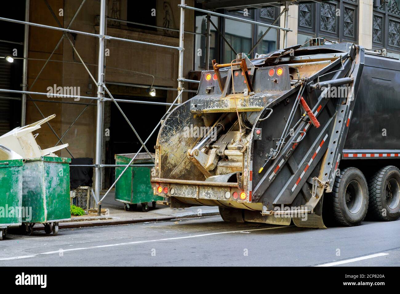 Green dumpster carts filled with construction debris collector truck
