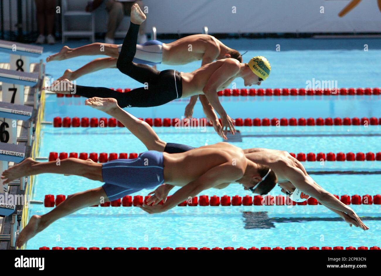 Swimmers display different styles as they dive into the pool for the 1500 meter freestyle semifinals at the U.S. Olympic Swimming Trials in Long Beach, California, July 13, 2004. From left are swimmers Christian Sprang (Gloucester County swim club), John Koehler (Dayton Raiders), Nathan Knopf (Auburn Aquatics/Lakeside), and Christopher George (Bolles School Sh). REUTERS/Lucy Nicholson  LN Stock Photo