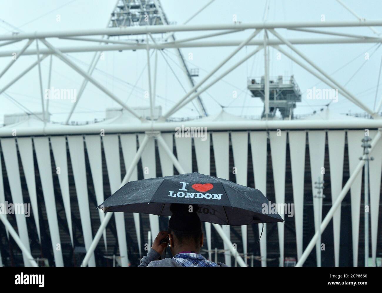 A worker uses an umbrella outside the Olympic Stadium at the Olympic Park in Stratford, the location of the London 2012 Olympic Games, in east London July 20, 2012. REUTERS/Toby Melville  (BRITAIN - Tags: SPORT OLYMPICS) Stock Photo