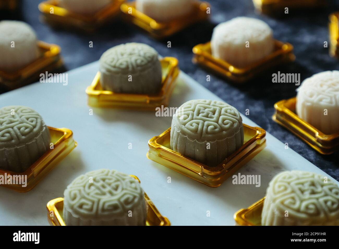 Snowskin Mooncakes in the Midst of Packaging Process. Placed on Golden Plastic Container; Ready to Capped and Sealed Stock Photo