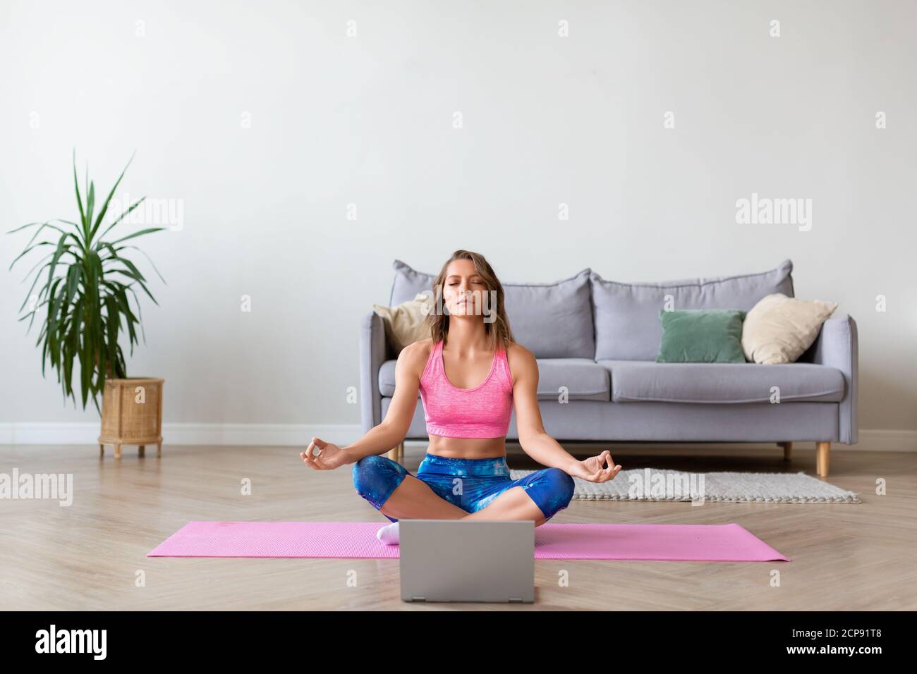 Online yoga lesson. Woman in lotus position in front of laptop monitor ...