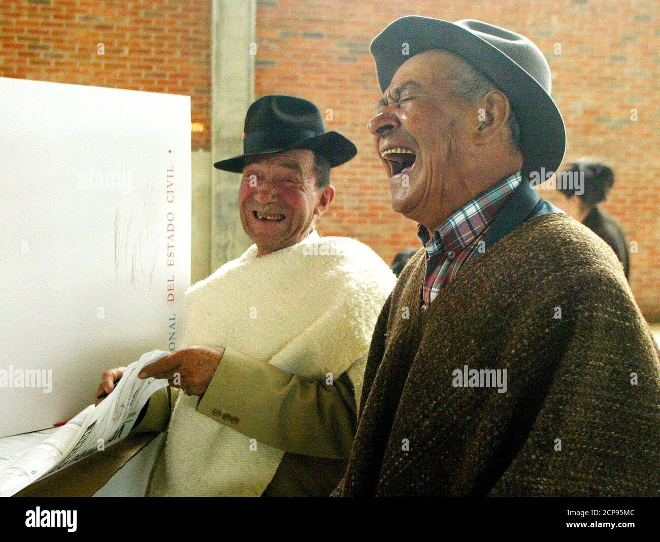 Two Colombians read the referendum in Guasca, Cundinamarca province, October 25, 2003. Colombians vote on Saturday on a crucial 15-point referendum that President Alvaro Uribe hopes will save the government $7 billion over seven years and reduce corruption. REUTERS/Daniel Munoz  DM/SV Stock Photo