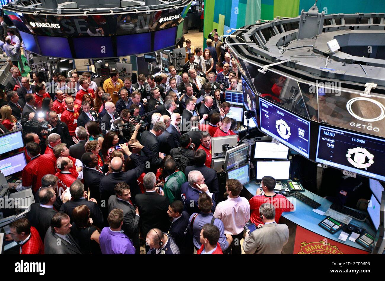 People gather at the post for the start of trading of Manchester United Ltd following it's initial public offering on the floor of the New York Stock Exchange, August 10, 2012. Shares in Manchester United priced below expectations and were essentially flat in early trading on Friday, a disappointing stock market debut for the world's most famous soccer club and most valuable sporting team. REUTERS/Brendan McDermid (UNITED STATES - Tags: BUSINESS SPORT SOCCER) Stock Photo