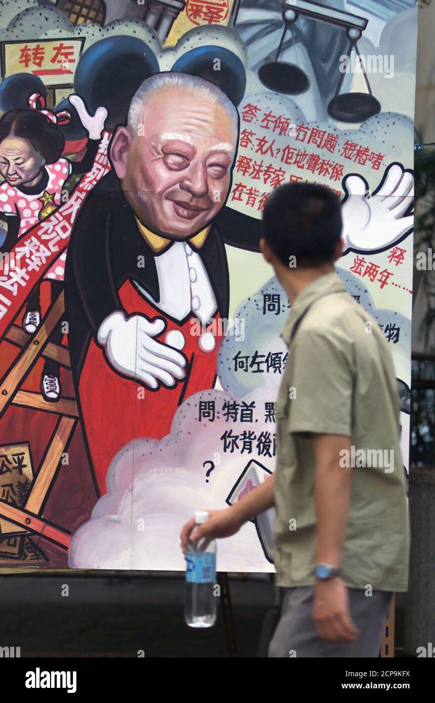 A passerby looks at a poster at a rally mocking Hong Kong leader Tung Chee-hwa and Chief Justice Elsie Leung June 26, the day marking the 1st anniversary of the re-interpretation of the territory's Basic Law. China reinterpreted crucial Hong Kong immigration laws on June 26, 1999, which reversed a ruling by the territory's highest court. Tung had encouraged Beijing to curb the right of entry of immigrants because he claimed it would have led to over 1.5 million mainland Chinese migrants crossing into the already crowded territory.  BY/CC Stock Photo