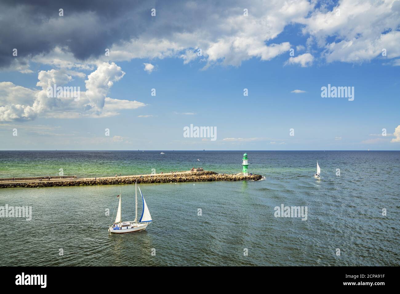 Sailing boat in front of lighthouse on the pier, harbor entrance in Warnemünde, Hanseatic City of Rostock, Baltic Sea coast, Mecklenburg-Western Pomer Stock Photo