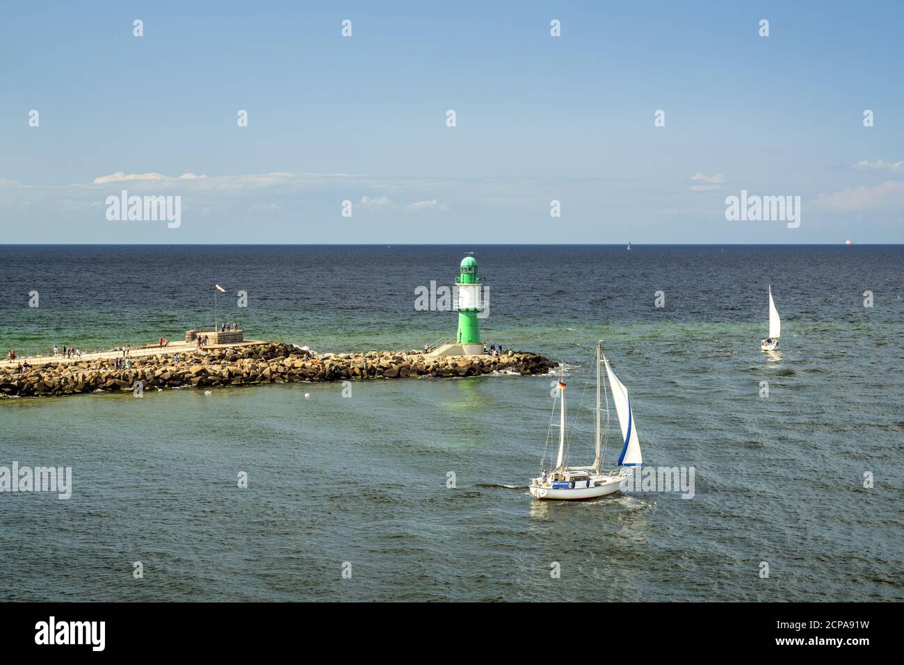 Sailing boat in front of lighthouse on the pier, harbor entrance in Warnemünde, Hanseatic City of Rostock, Baltic Sea coast, Mecklenburg-Western Pomer Stock Photo