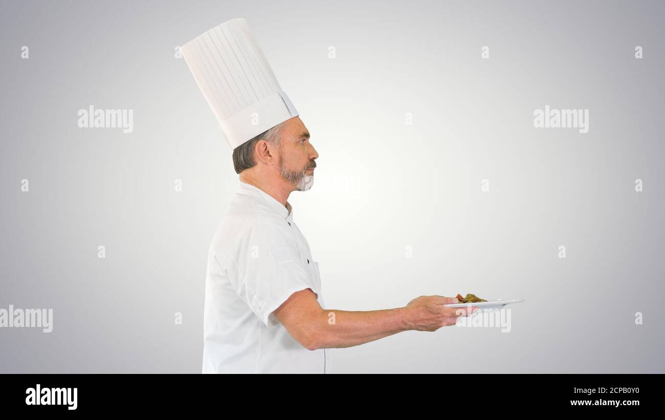 Male chef white uniform running with a plate of salad on gradien Stock Photo