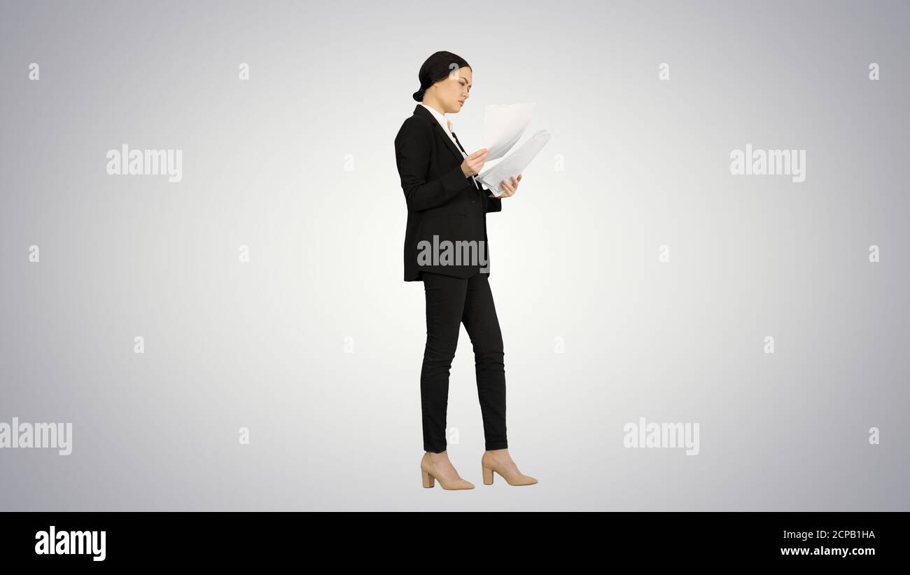 Serious Brunette Businesswoman reading documents on gradient bac Stock Photo