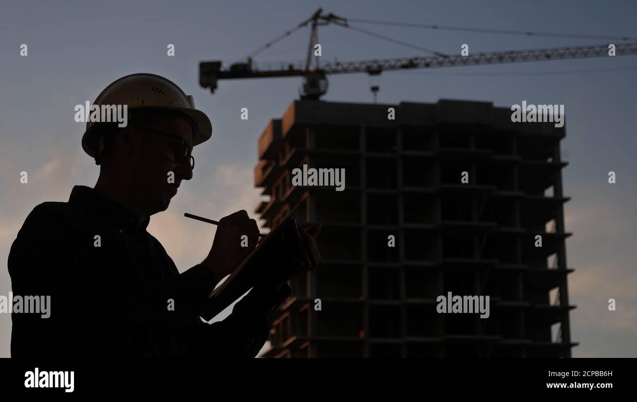Engineer in a helmet writing check list. Stock Photo