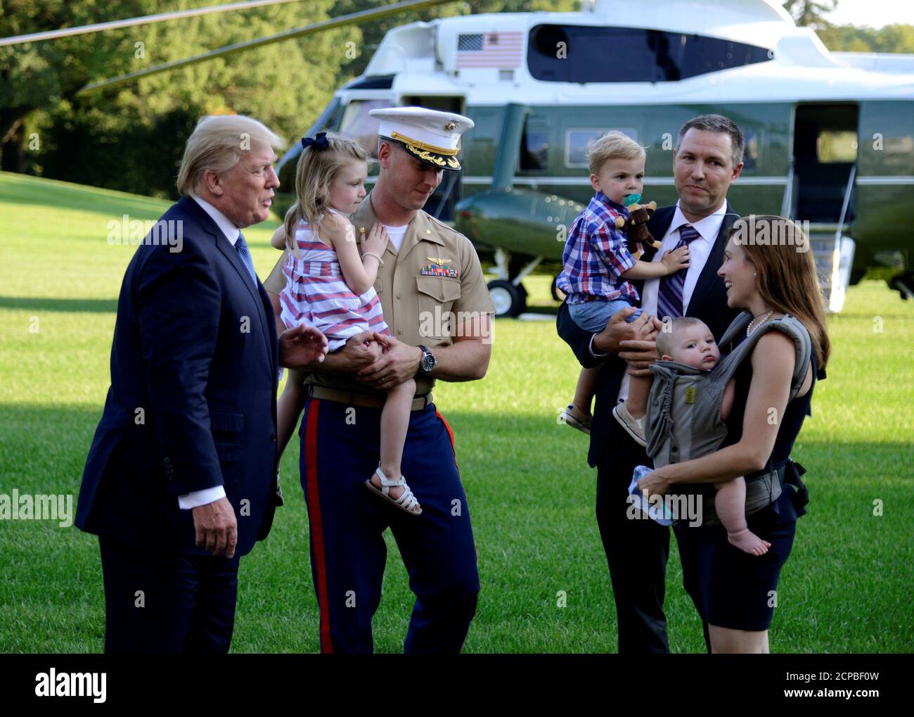 U.S. President Donald Trump (L) welcomes the family of U.S. Marine Corps Maj. James Thompson, Jr., holding his daughter, London, 3, along with his wife Lynel, who is holding 7-month old son Joel, and brother Matt, who is holding son James III, as he announces Thompson's last Marine One flight, on his return to the White House, Washington, DC, U.S., from a week at the UN General Assembly and the weekend at his Bedminster New Jersey Golf Club, September 24, 2017.           REUTERS/Mike Theiler Stock Photo