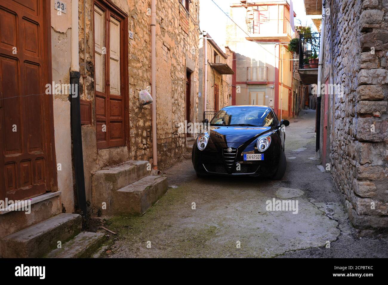 Black Alfa Romeo Mito in the narrow streets of Sicily. Car on very narrow and old streets in the mountain village of Sicily. Stock Photo