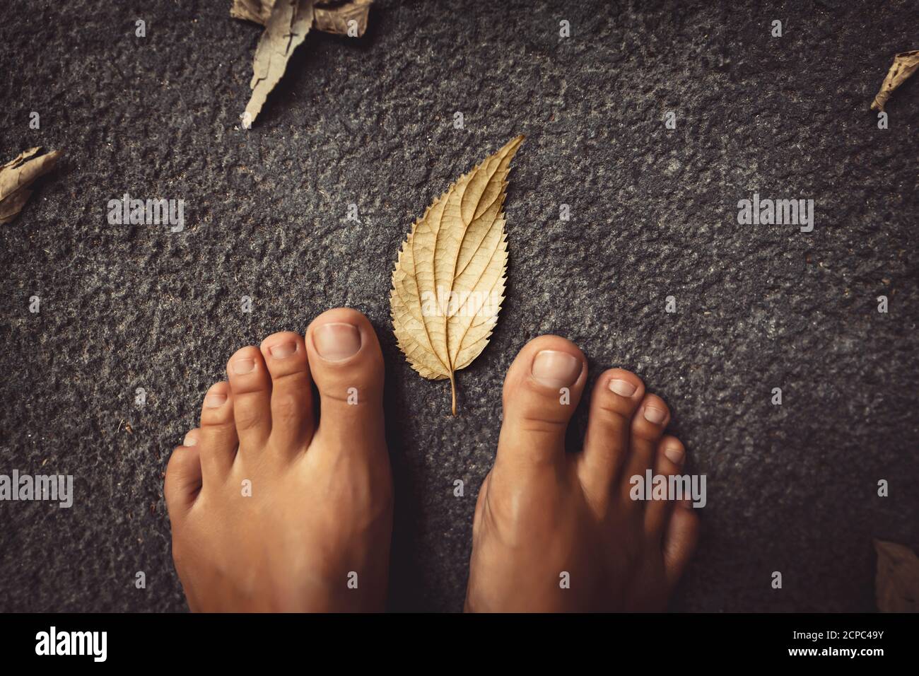 Welcome Fall Background. Closeup Concept Photo of a Barefoot Women Feet and Dry Leaves. Autumn Season Theme. Stock Photo