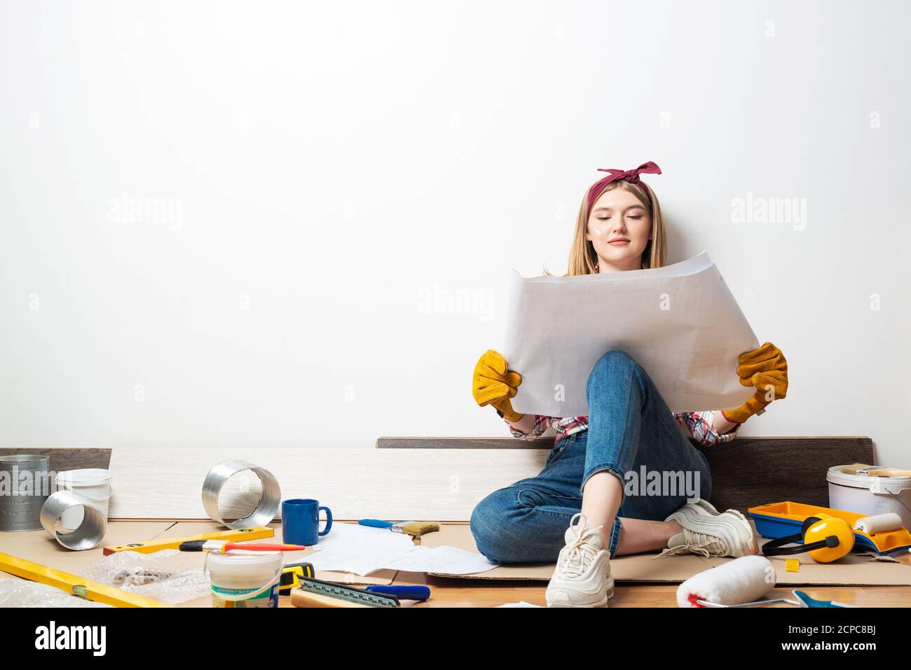 Happy girl sitting on floor with blueprint Stock Photo - Alamy