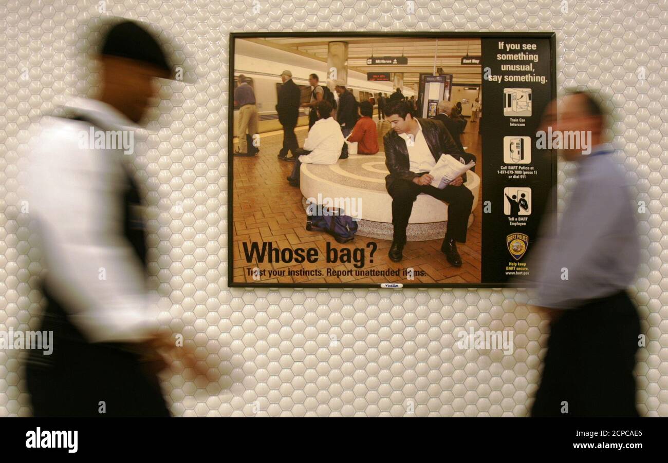 People walk past an anti-terrorism billboard in a Bay Area Rapid Transit (BART) metro station in San Francisco, California June 22, 2004. BART will be installing more than 150 billboards throughout the bay area stations as part of an anti-terrorism awareness campaign designed to put passengers on alert for unattended and suspicious bags as well as suspicious behavior. REUTERS/Kimberly White  KW Stock Photo