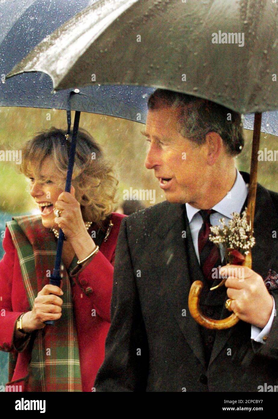 Prince Charles and his new wife, Camilla Parker Bowles, shelter from the rain after opening a new play park in Ballater.  Prince Charles and his new wife, Camilla Parker Bowles, shelter from the rain after opening a new play park in Ballater April14, 2005. Prince Charles and Camilla broke off from their honeymoon on Thursday for their first married engagement together. REUTERS/David Ceskin/Pool Stock Photo