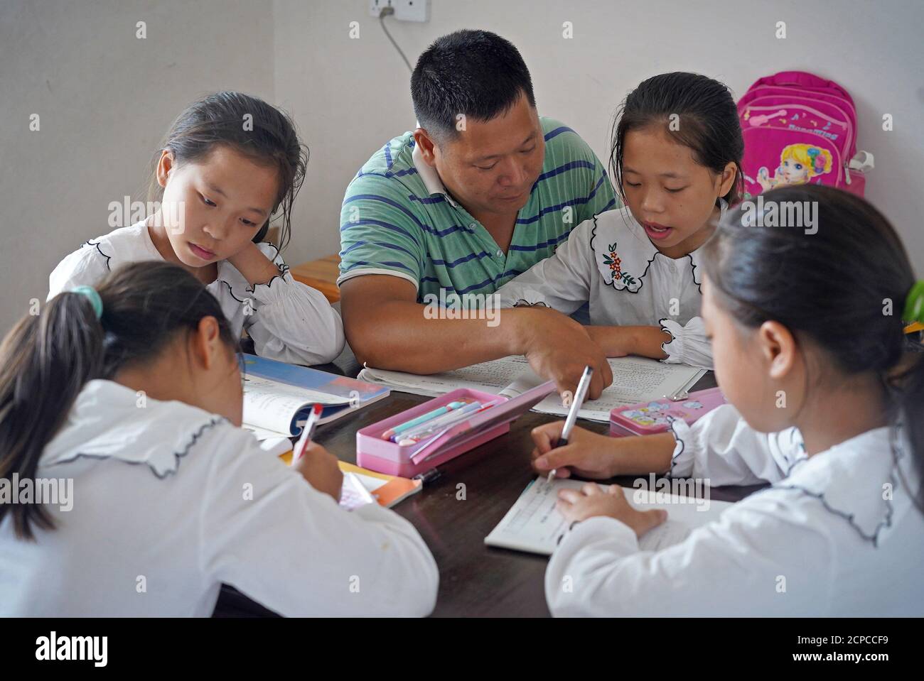 (200919) -- GANZHOU, Sept. 19, 2020 (Xinhua) -- Wu Nianyou guides his daughters in doing homework in Shangbao Village, Ganzhou City of east China's Jiangxi Province, Sept. 9, 2020. Wu Nianyou, a farmer in Shangbao Village of Ganzhou City, and his wife saw their quadruplet daughters come to the world on a morning in September 2010. They named their daughters Wu Mengling, Wu Mengting, Wu Mengyun and Wu Mengqin, who became their worry to raise up with little income only from the fields. Being premature babies, the girls were in poor health conditions which needed lots of money to treat. With the Stock Photo