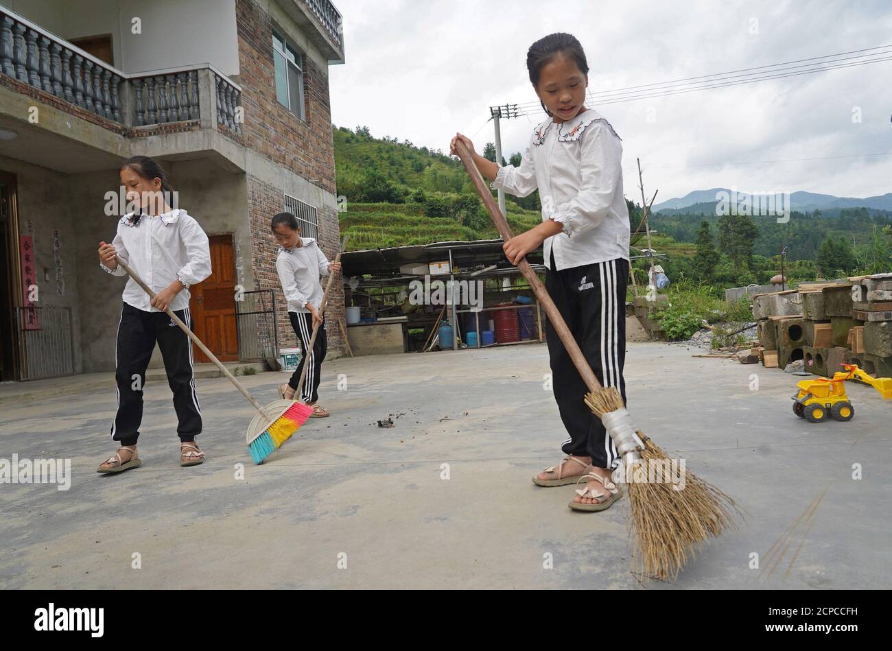 (200919) -- GANZHOU, Sept. 19, 2020 (Xinhua) -- The quadruplet girls clean the yard at home in Shangbao Village, Ganzhou City of east China's Jiangxi Province, Sept. 10, 2020. Wu Nianyou, a farmer in Shangbao Village of Ganzhou City, and his wife saw their quadruplet daughters come to the world on a morning in September 2010. They named their daughters Wu Mengling, Wu Mengting, Wu Mengyun and Wu Mengqin, who became their worry to raise up with little income only from the fields. Being premature babies, the girls were in poor health conditions which needed lots of money to treat. With the help Stock Photo