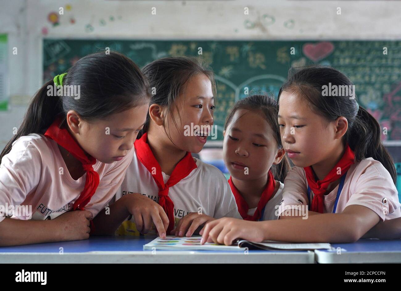 (200919) -- GANZHOU, Sept. 19, 2020 (Xinhua) -- The quadruplet girls read a book at the classroom in Shangbao Village, Ganzhou City of east China's Jiangxi Province, Sept. 10, 2020. Wu Nianyou, a farmer in Shangbao Village of Ganzhou City, and his wife saw their quadruplet daughters come to the world on a morning in September 2010. They named their daughters Wu Mengling, Wu Mengting, Wu Mengyun and Wu Mengqin, who became their worry to raise up with little income only from the fields. Being premature babies, the girls were in poor health conditions which needed lots of money to treat. With the Stock Photo