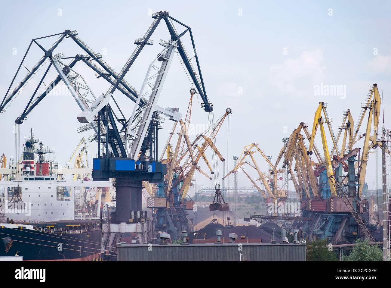 Cranes at the cargo sea port loading the bulk carrier with iron ore or coal Stock Photo