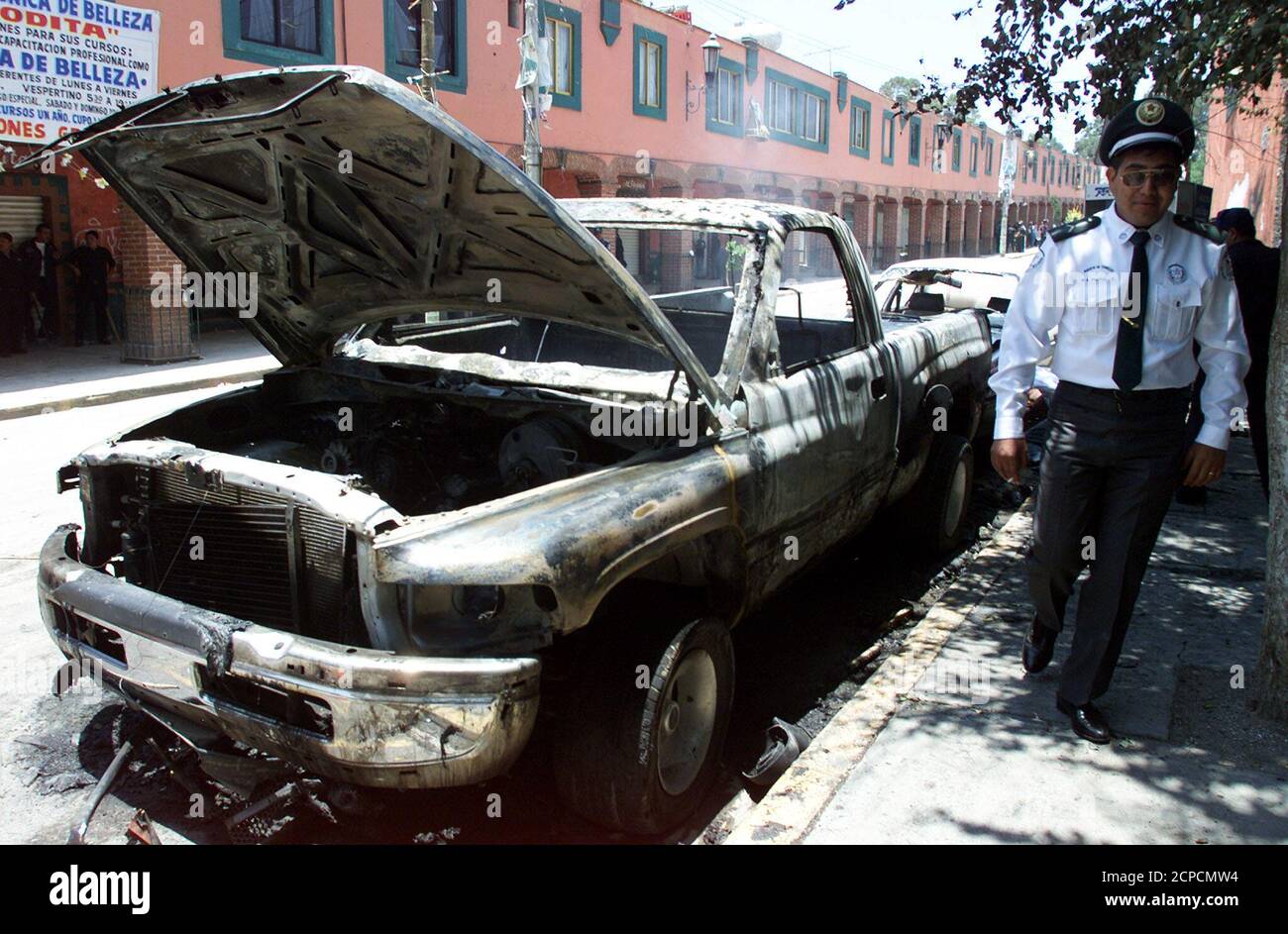 A policeman walks past a burnt out pick-up truck in the outlying Mexico City suburb of Chimalhuacan after a riot which left six people dead August 18, 2000. Rival factions of the long ruling PRI party clashed over control of the local town hall after supporters of the elected mayor and followers of a local PRI matriarch known as La Loba (the She Wolf) exchanged gunfire.  AW Stock Photo