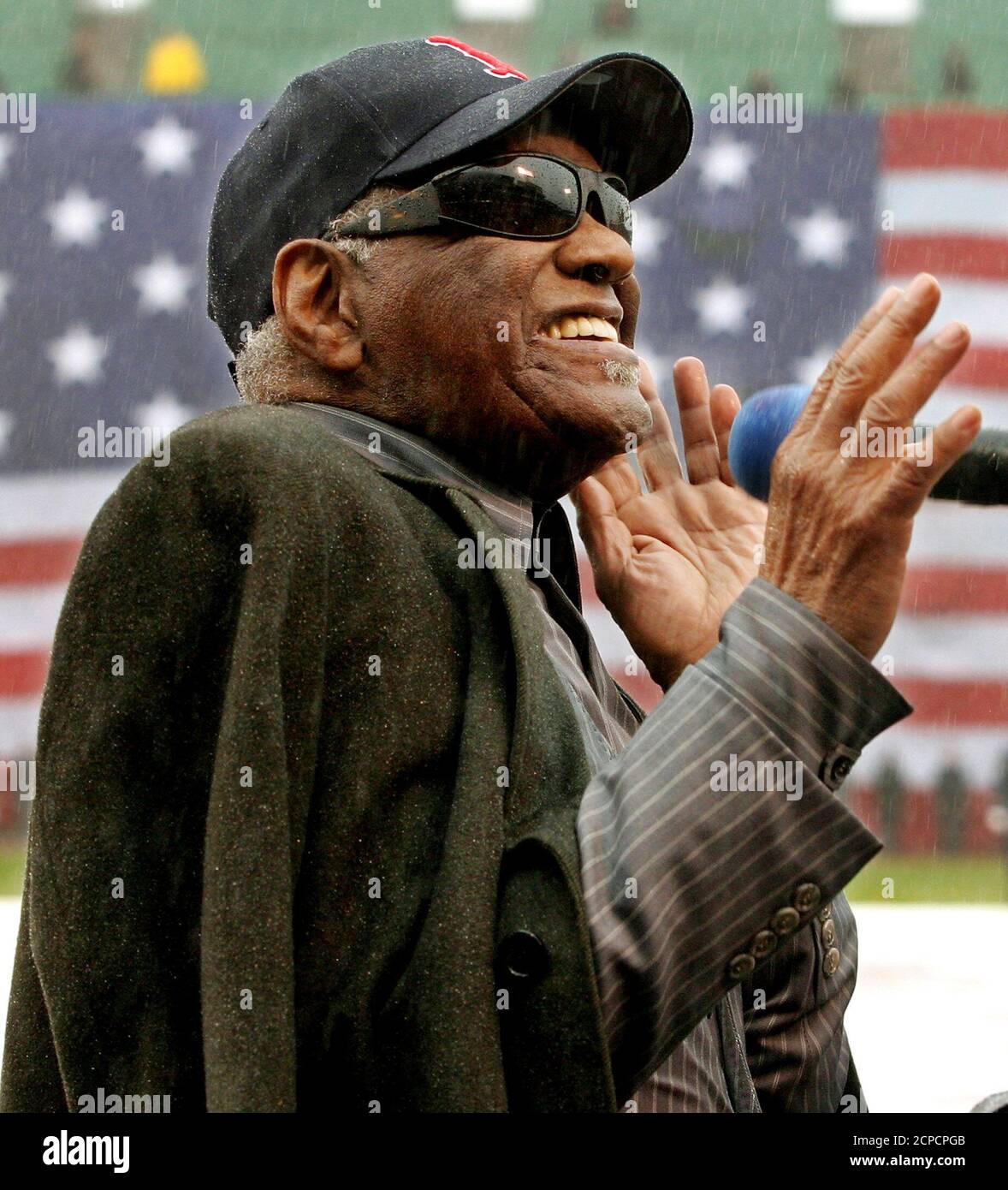 Entertainer Ray Charles sings 'America the Beautiful' in the pouring rain as a giant United States flag covers Fenway Park's renowned 'Green Monster' left field wall during Opening Day ceremonies April 11, 2003 in Boston. The game between the Boston Red Sox and the Baltimore Orioles was called off and delayed until another day due to the heavy rain. REUTERS/Jim Bourg  JRB Stock Photo