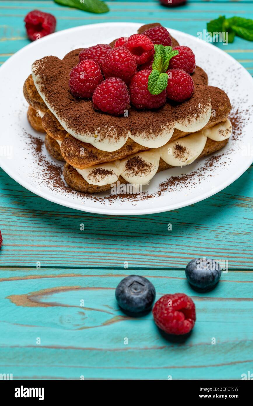 portion of Classic tiramisu dessert with raspberries and blueberries on ...