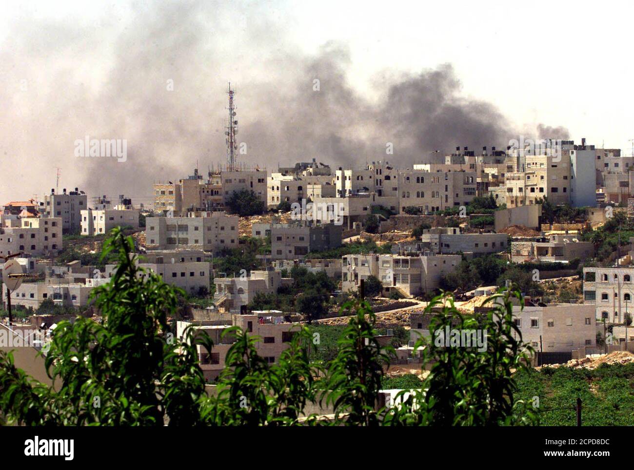 Smoke rises over the West Bank city of Hebron June 26, 2002 during shelling of the Palestinian police building by Israeli forces. Israel kept Palestinians in seven West Bank cities under the gun and threatened to expand the operation. The Palestinian Authority, under pressure from U.S. President George W. Bush to dump Yasser Arafat as its leader, announced that presidential elections would be held next January. REUTERS/Nayef Hashlamoun RS/CLH/ Stock Photo