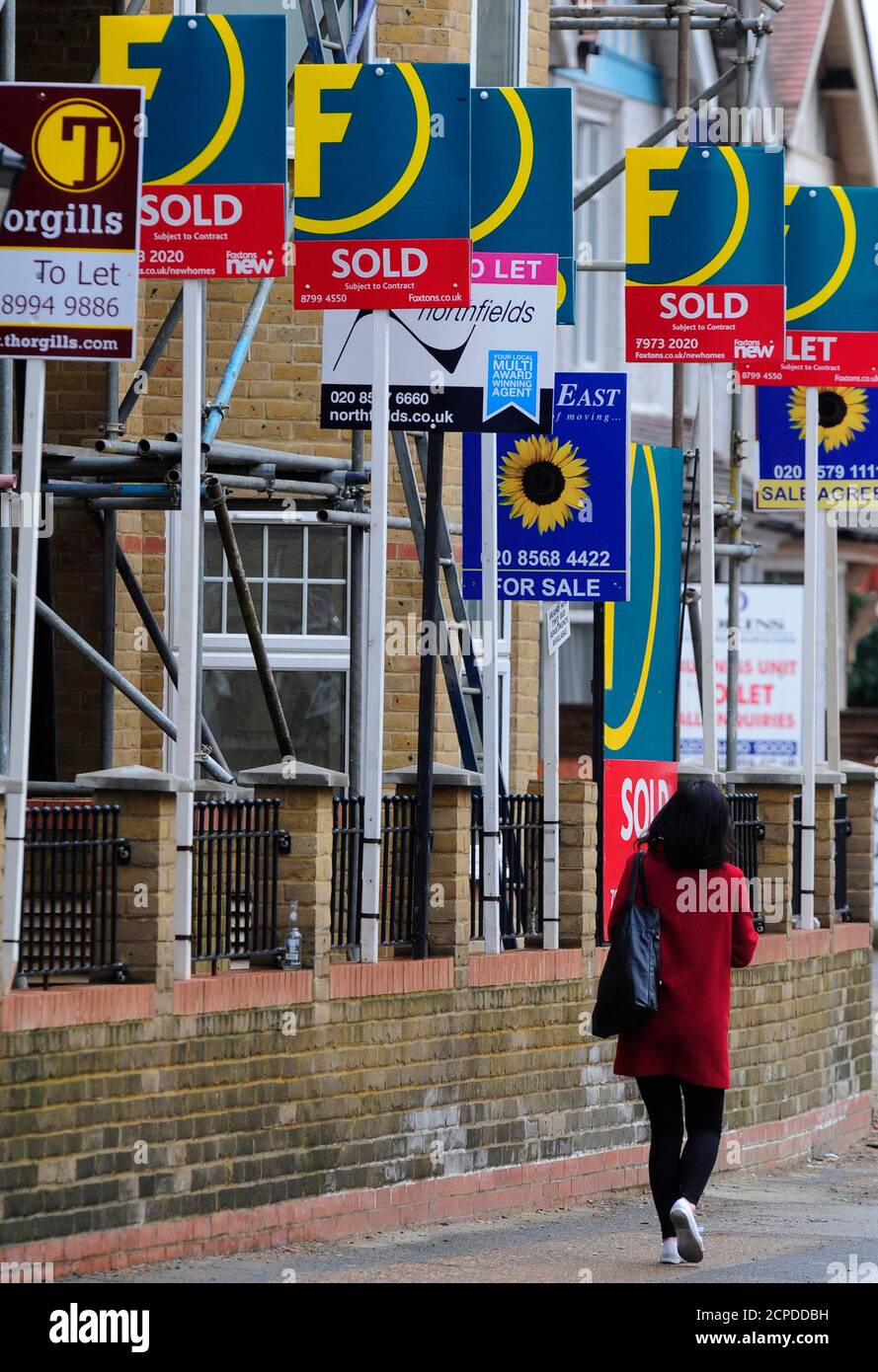 A woman passes house sales and letting signs in west London February 9, 2010. Property price rises in Britain picked up pace in January, even as unusually heavy snowfall led to a sharp drop in new buyer enquiries, a survey indicated on Tuesday.     REUTERS/Toby Melville (BRITAIN - Tags: BUSINESS) Stock Photo