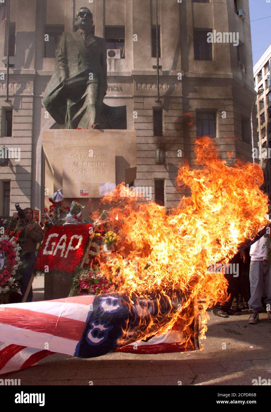 A U.S. flag burns in front of the statue of President Salvador Allende next  to the La Moneda presidential palace in Santiago, September 11, 2002.  Socialists and communists clashed during a ceremony