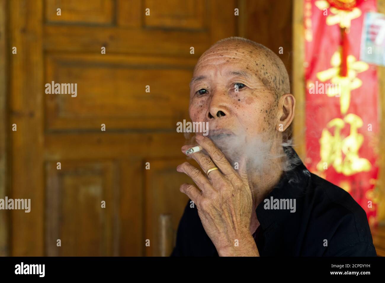 An old man smokes in Dazhai village. Stock Photo