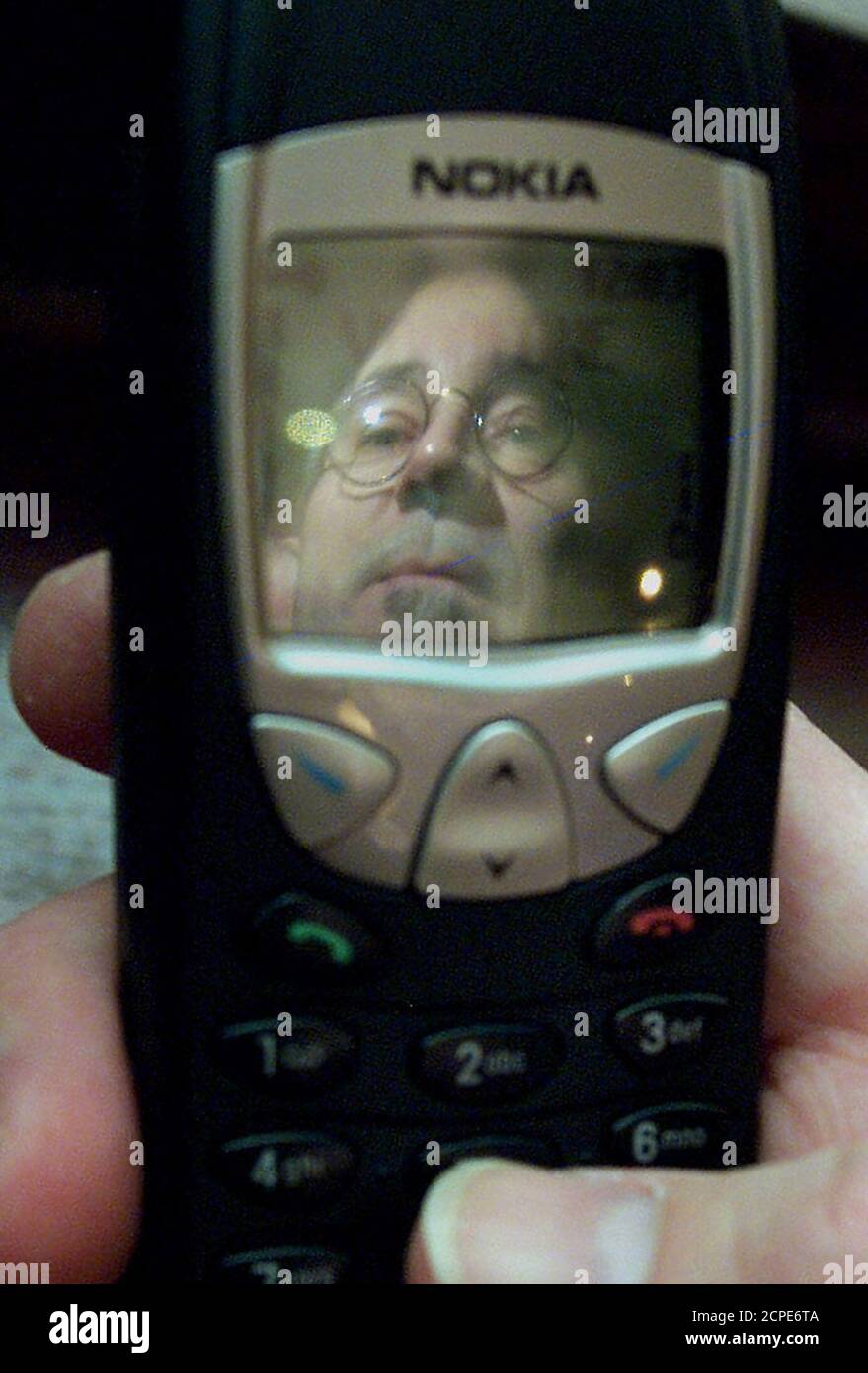 Mobile phone user, Australian Daniel Davis, is reflected on the screen of his handset in central London, January 25, 2002. Britain launched a 7.4 million pound ($10.5 million) research programme on Friday to investigate whether mobile phones pose a health risk. REUTERS/Ferran Paredes  FP/ASA Stock Photo