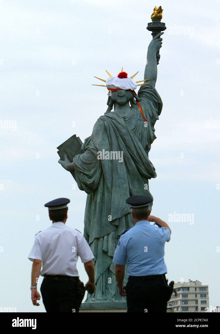 French police look up at a French navy sailor's bonnet which rests on the  head of the replica of the Statue of Liberty located on a narrow island in  the River Seine