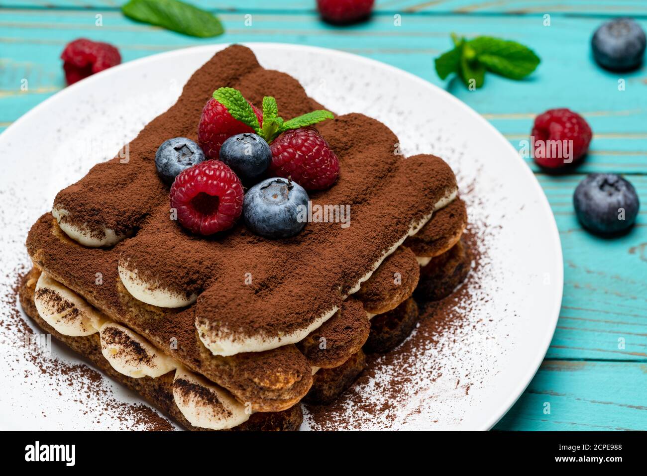 portion of Classic tiramisu dessert with raspberries and blueberries on ...