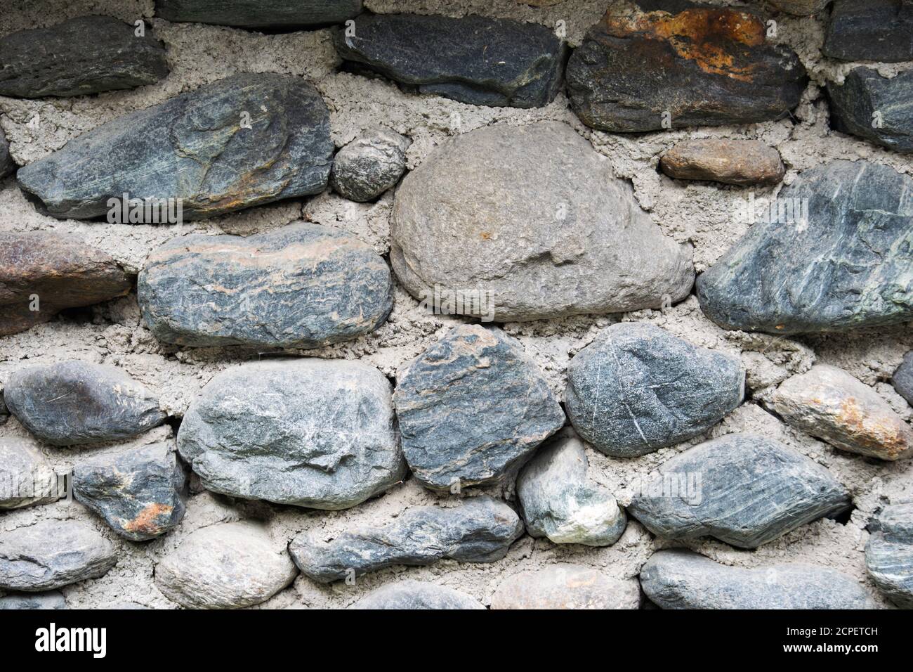 fragment of stone wall lined with cobblestones background texture Stock Photo