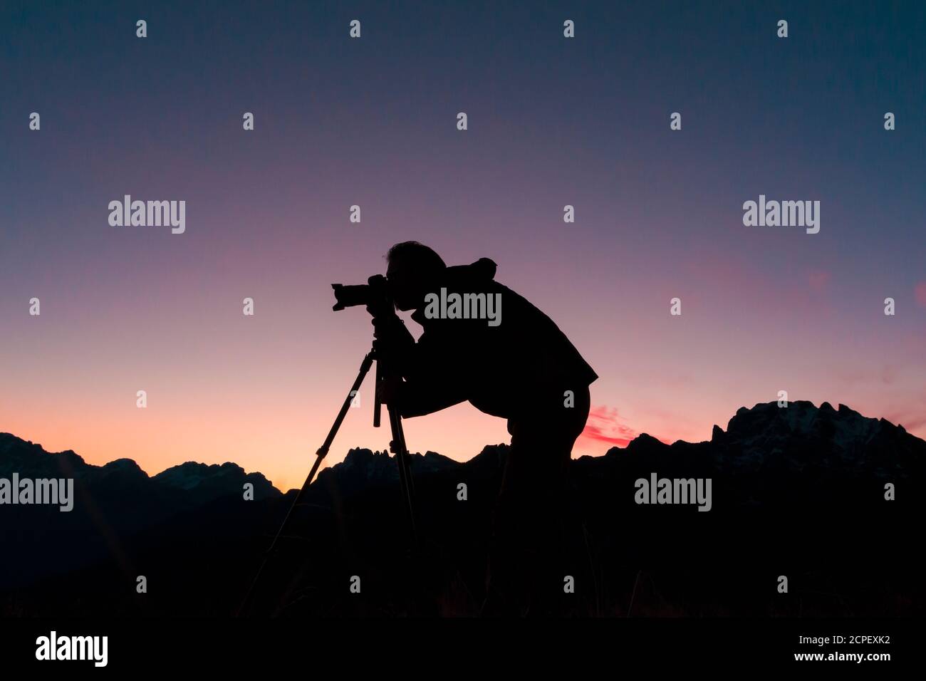 Silhouette of photographer taking pictures in mountain at sunrise Stock Photo