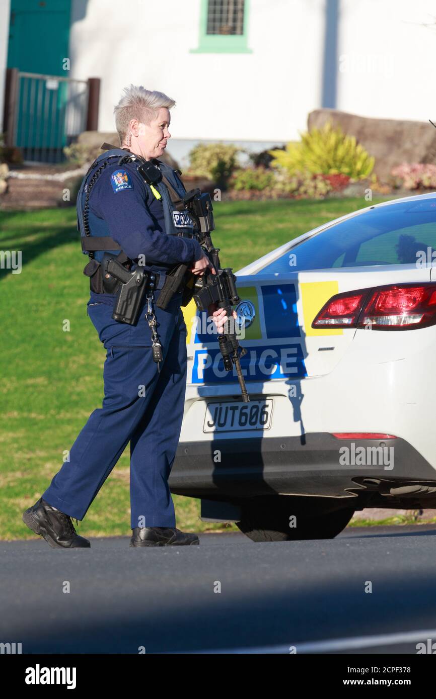 A female member of the New Zealand Police standing behind a police car holding an assault rifle. Tauranga, New Zealand, June 22 2018 Stock Photo
