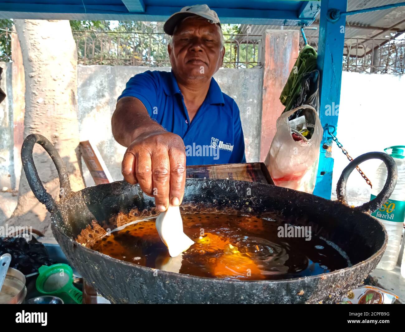 DISTRICT KATNI, INDIA - JANUARY 18, 2020: An indian old man frying samosa in the oil pan at street food corner. Stock Photo