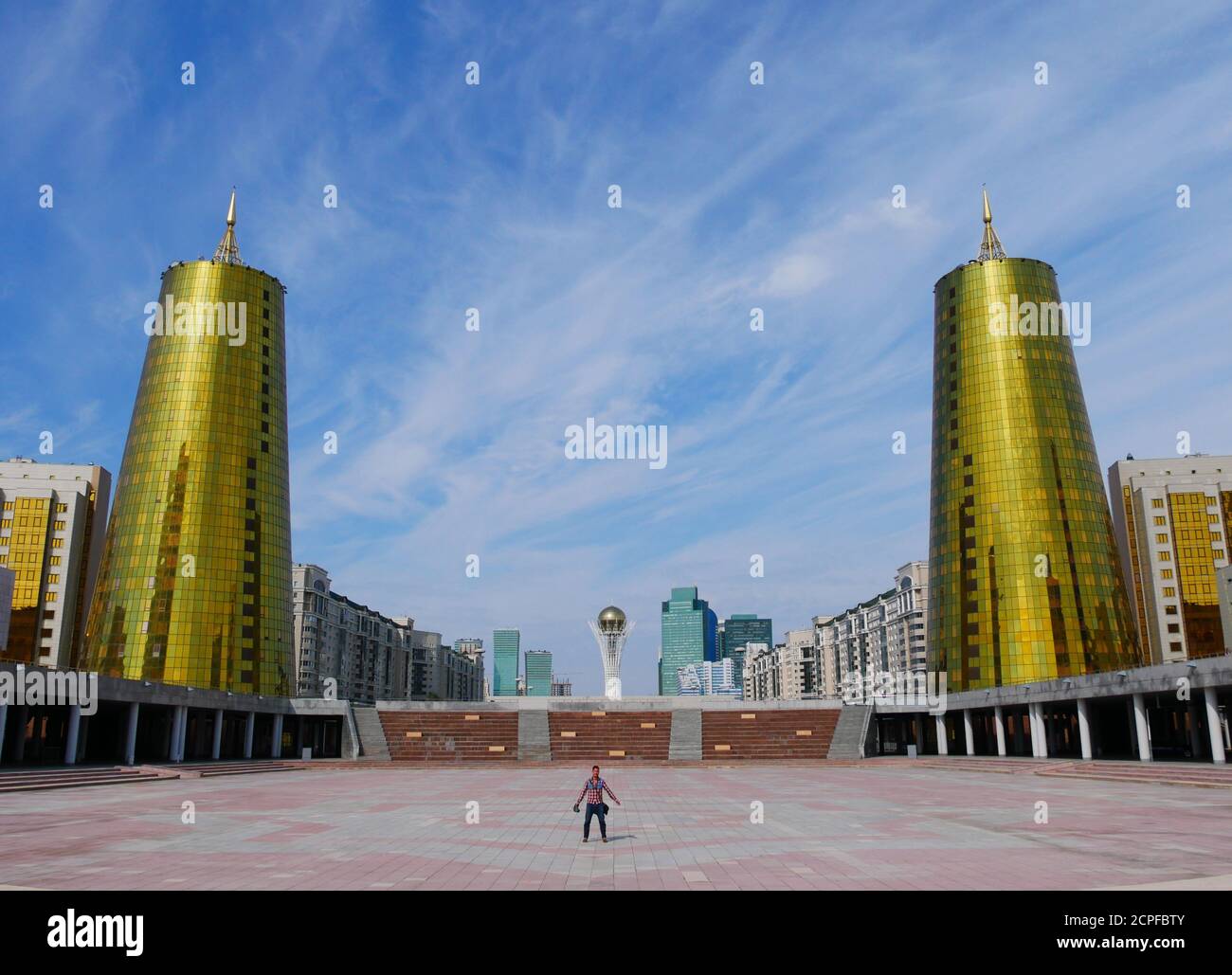 Nur-Sultan, Kazakhstan - 2 Sep 2019: A man stands on a city square in Nur-Sultan's (Astana's) city center with the city skyline in the background. Stock Photo